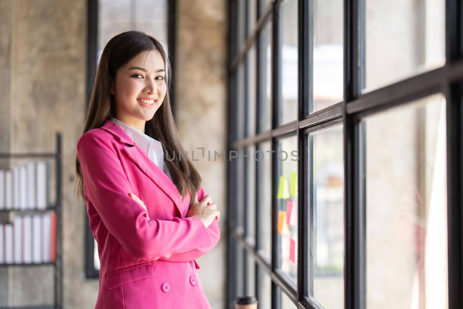 Young confident smiling Asian business woman leader, successful entrepreneur, elegant professional company executive ceo manager, wearing suit standing in office with arms crossed.