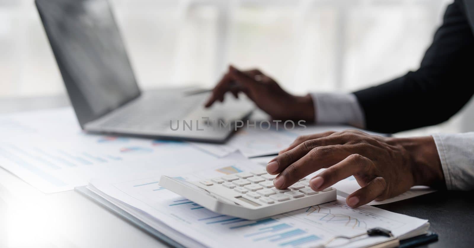 Close up Businessman using calculator and laptop for calculating finance, tax, accounting, statistics and analytic research concept..