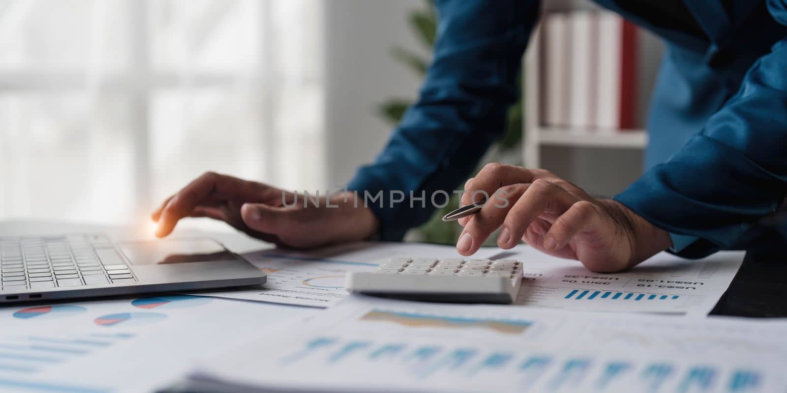 Close up Businessman using calculator and laptop for calculating finance, tax, accounting, statistics and analytic research concept..