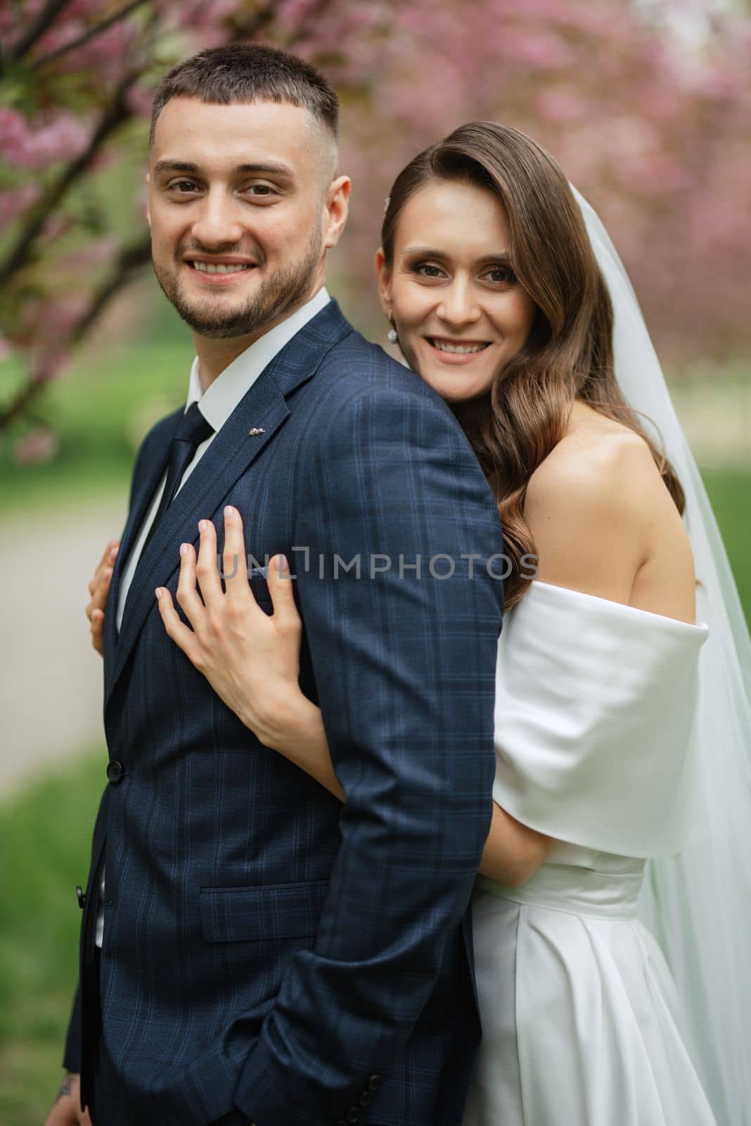 newlyweds walk in the park among cherry blossoms by Andreua