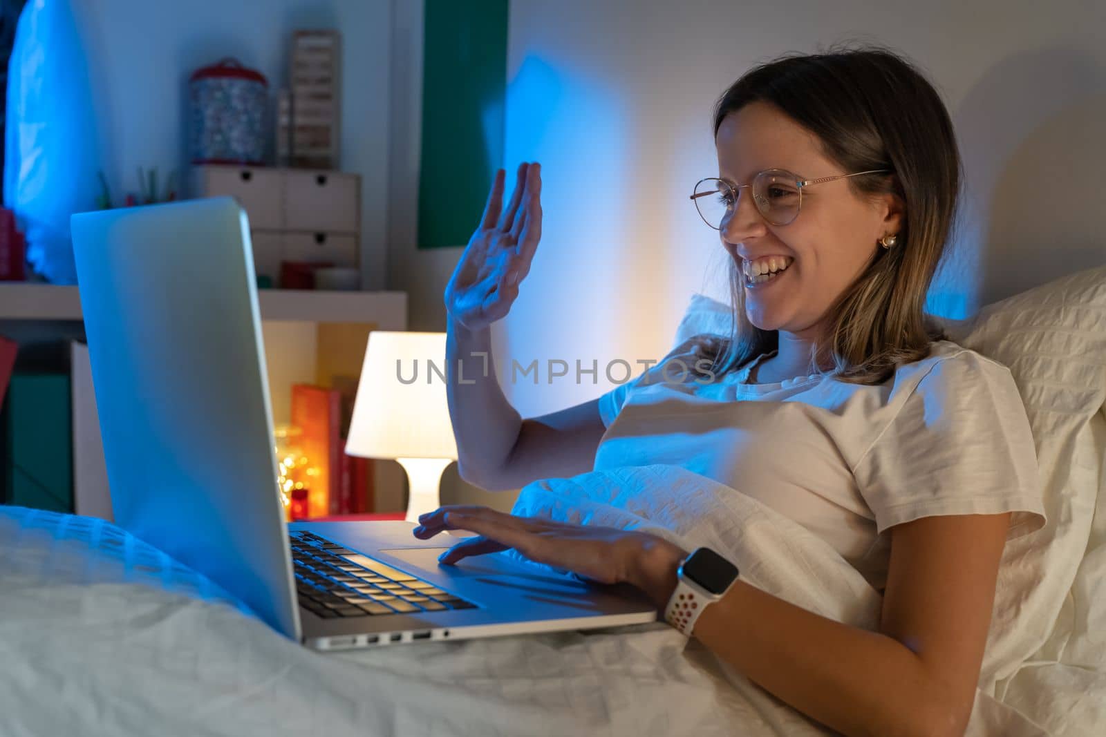 Beautiful young girl sitting on bed at night working with her laptop in the middle of the night. by PaulCarr