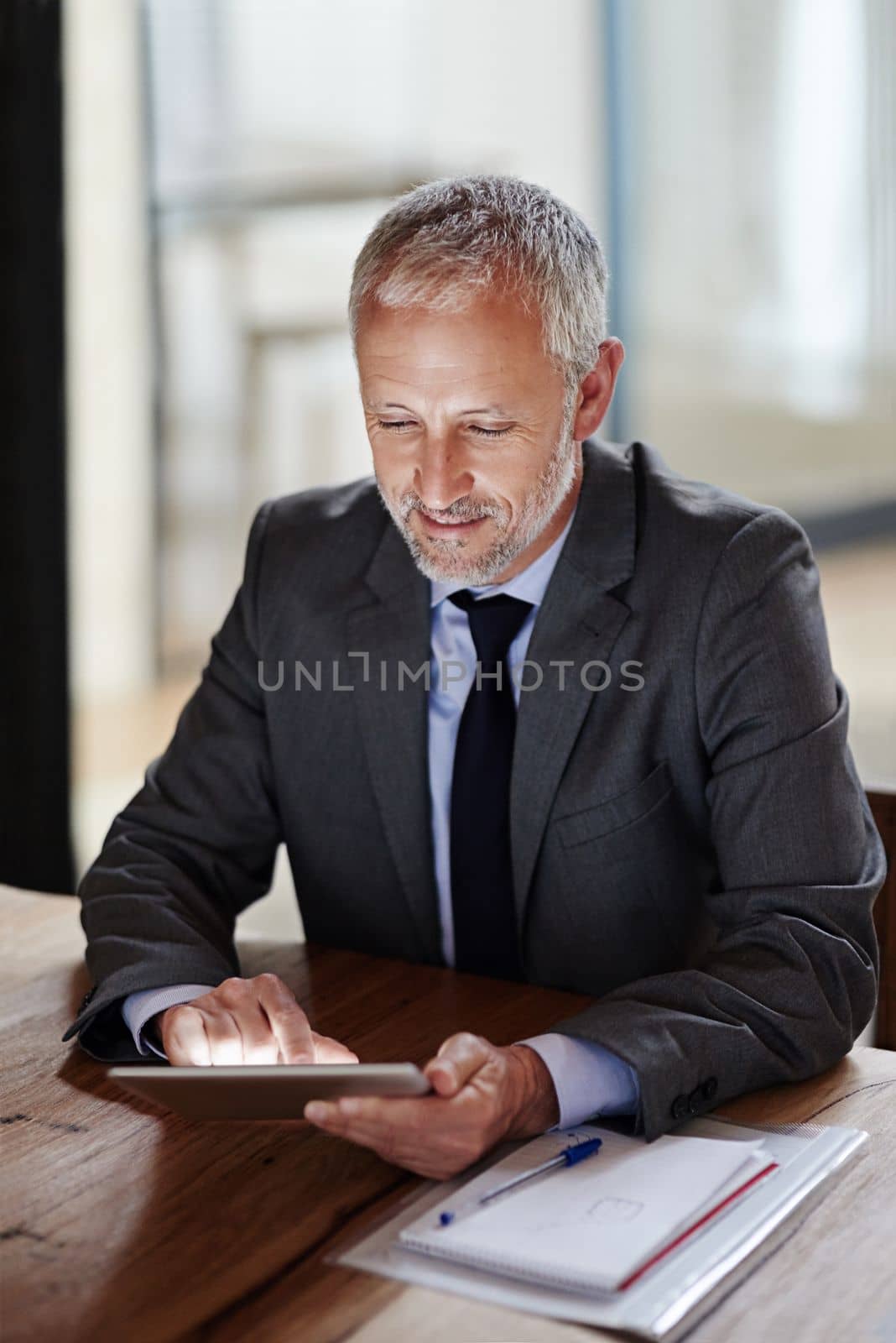 Technology helps him keep track of business. a mature businessman using a digital tablet in an office