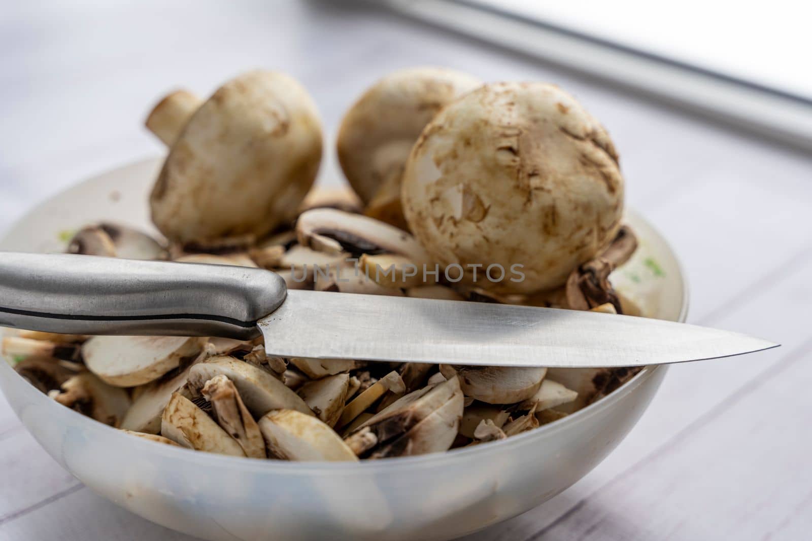 a bowl with pieces of fresh mushrooms. cut the mushrooms with a knife. Cooking mushroom dishes. Cooking dinner in the kitchen. Champignons