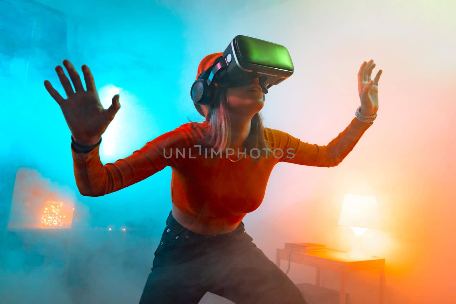 Wireless technologies. Young woman using virtual reality glasses in the dark room with neon lighting by PaulCarr