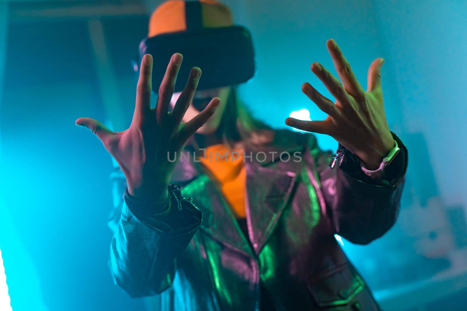 Wireless technologies. Young woman using virtual reality glasses in the dark room with neon lighting by PaulCarr