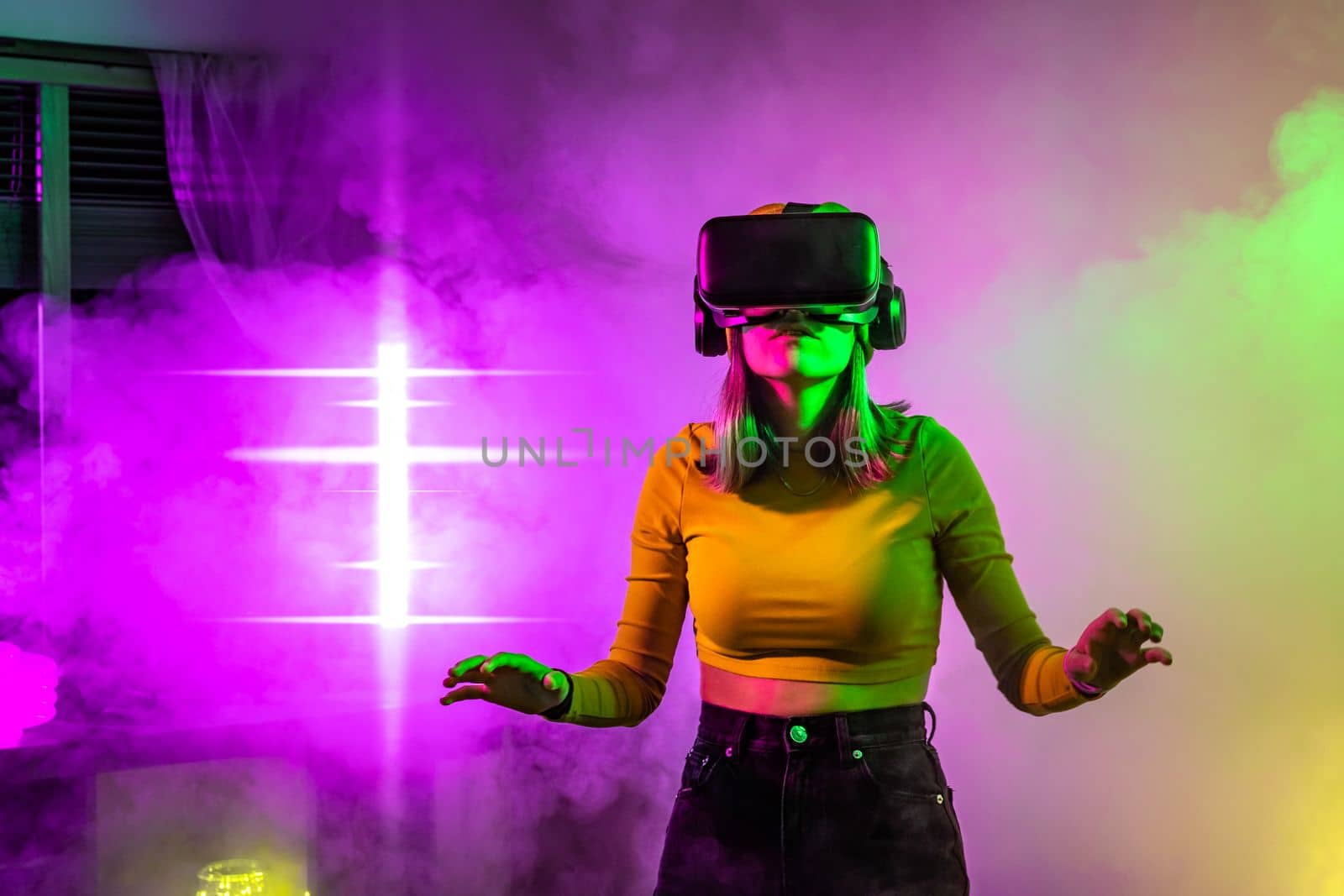 Wireless technologies. Young woman using virtual reality glasses in the room with neon lighting by PaulCarr