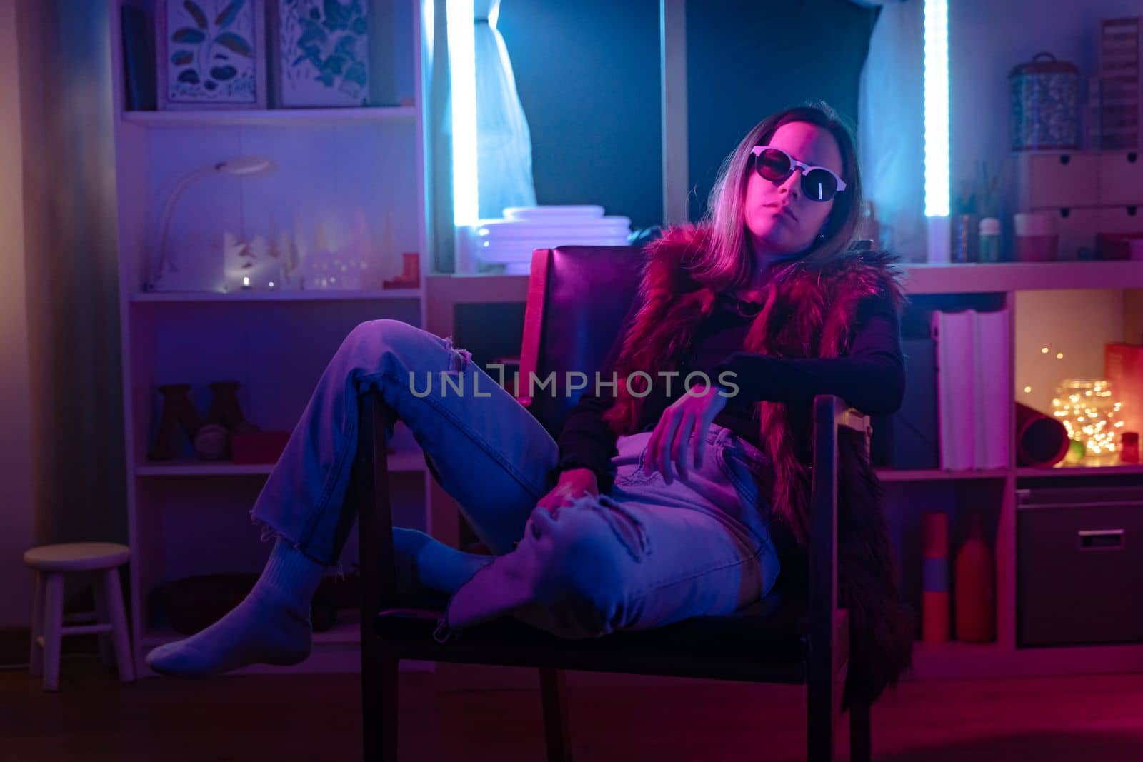 Beautiful girl looking to camera with sun glasses and fashion outfit in a room with colorful neon lights. by PaulCarr