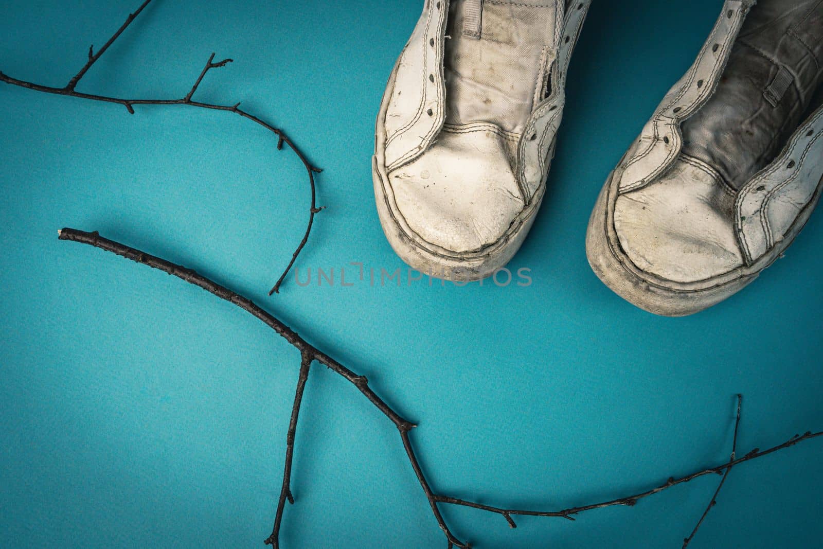 old battered women's sneakers without laces on a blue background. view from above. worn sneakers. High quality photo