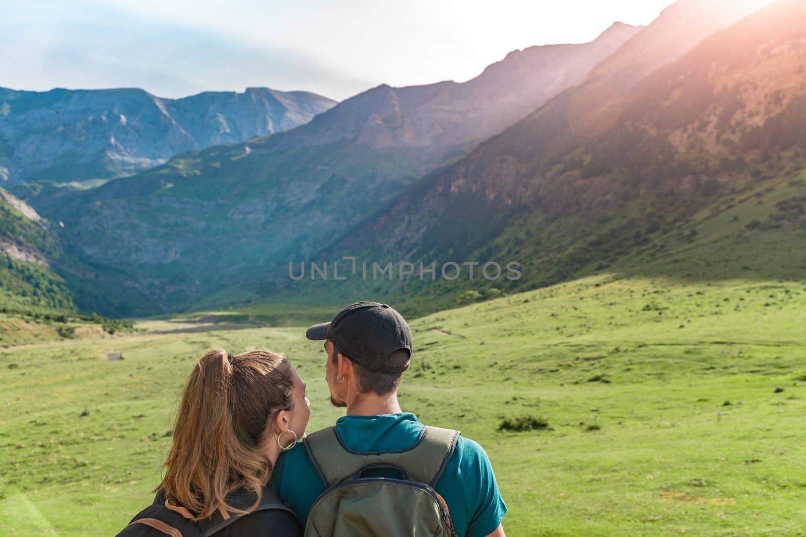 Young Couple in a beautiful valley between mountains during the sunset. Discovery Travel Destination and Freedom Concept. High quality photo.