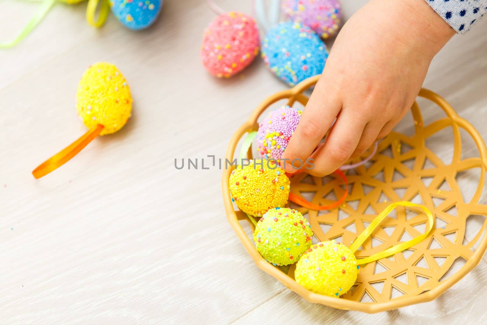Cute smiling little girl with basket full of colorful easter eggs