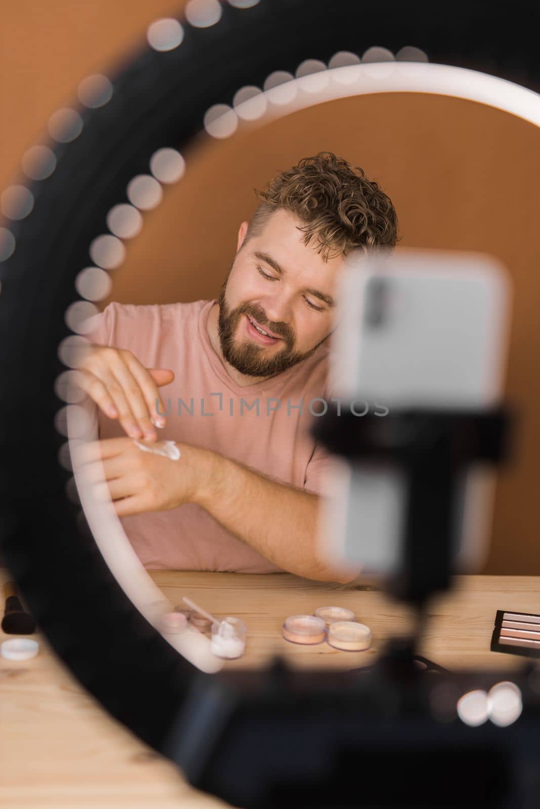 Man talking on cosmetics holding a makeup tools while recording his video. Guy making video for his blog on cosmetic product.