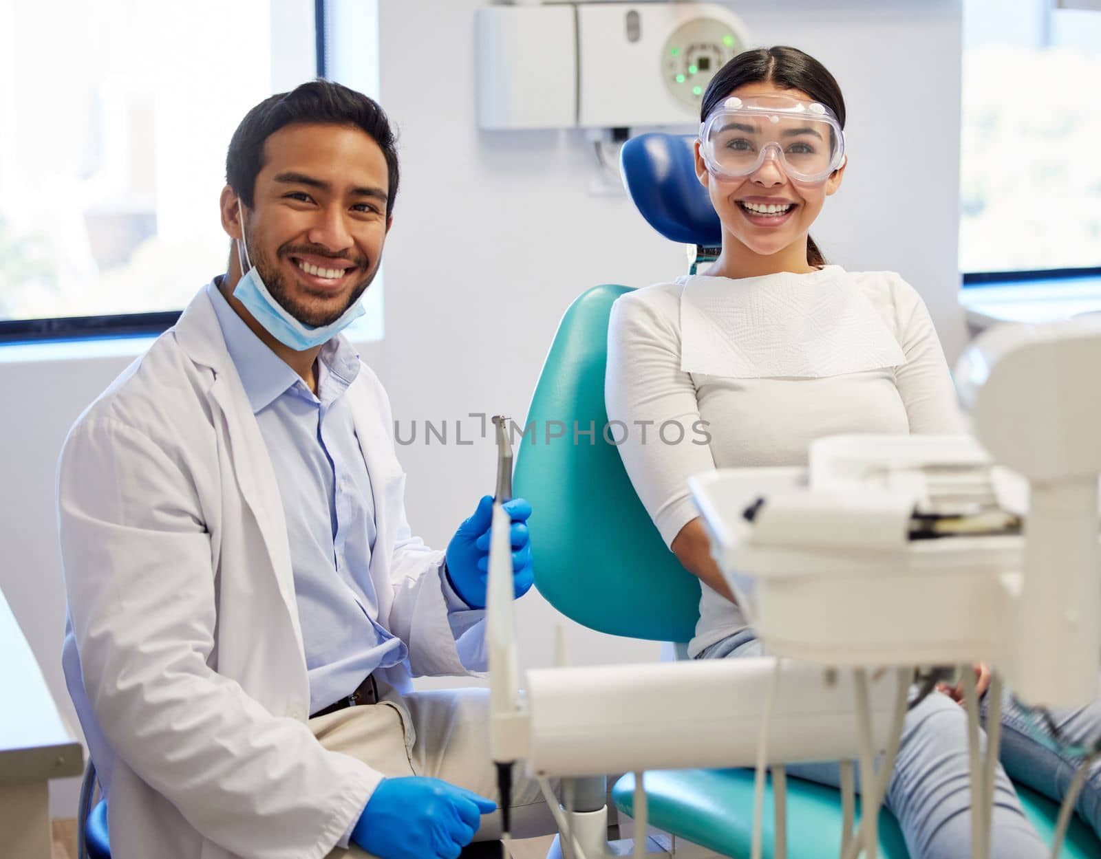 My teeth look amazing thanks to my dentist. Portrait of a young woman having a consultation with her patient in a dentists office. by YuriArcurs