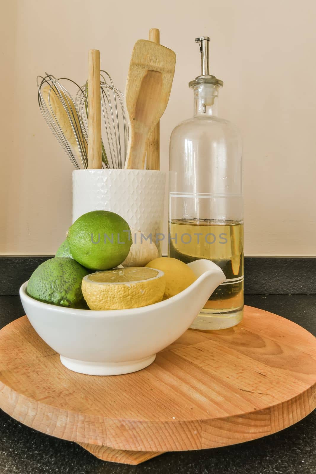some lemons and limes in a bowl on a wooden cutting board next to a bottle of olive oil