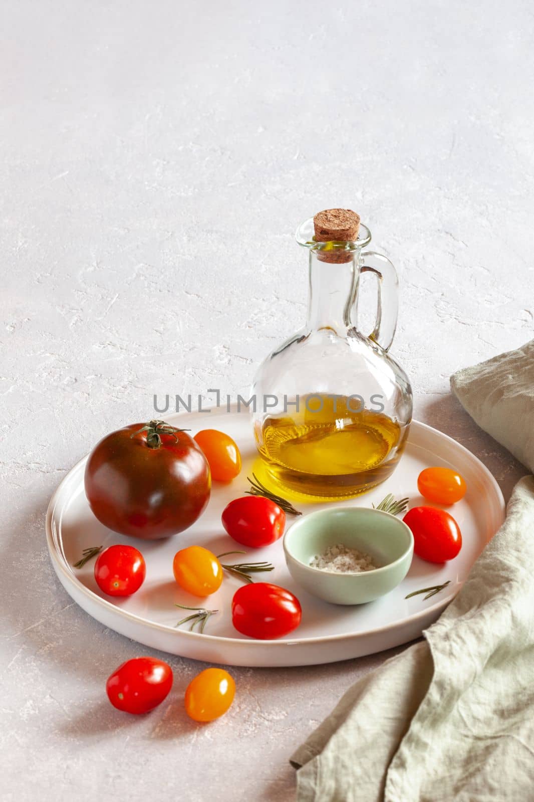 round tray with different tomato varieties, served with salt and olive oil, side view, copy space