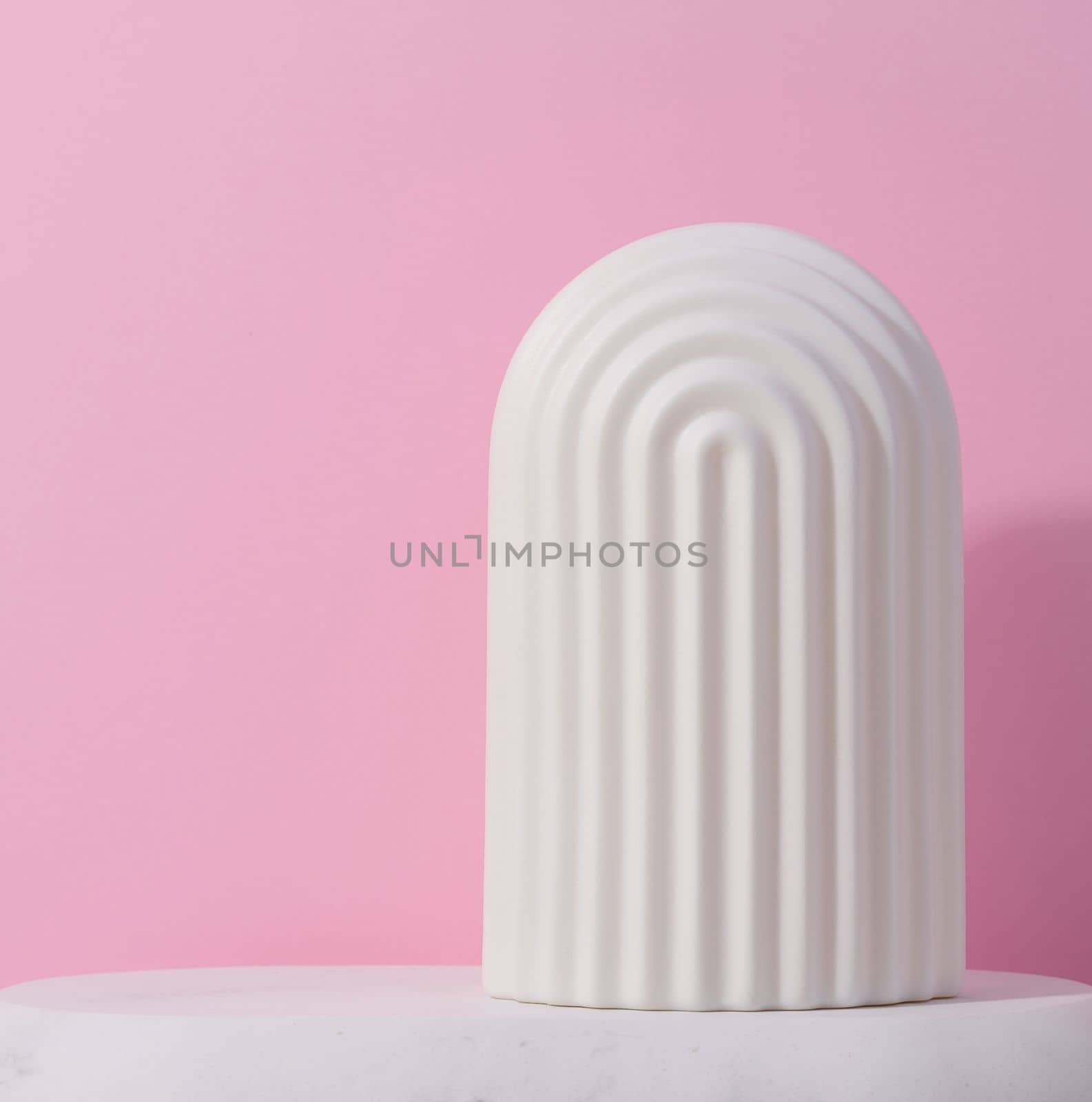 White ceramic decorative arch on a pink background, background for showcasing cosmetics, products, advertising and promotion