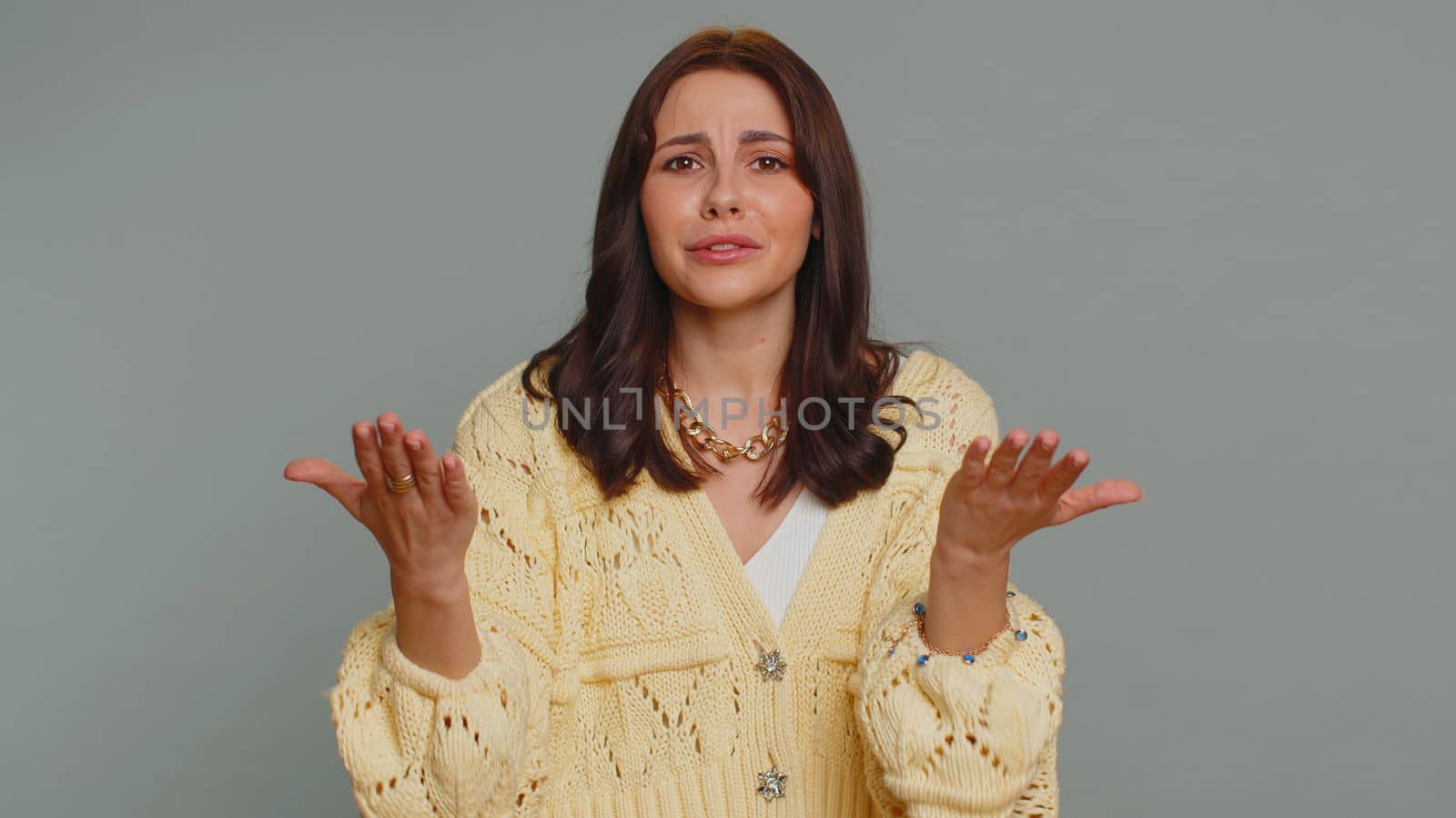 Quarrel. Displeased pretty young woman gesturing hands with irritation and displeasure, blaming scolding for failure, asking why this happened. Millennial girl isolated on gray studio background