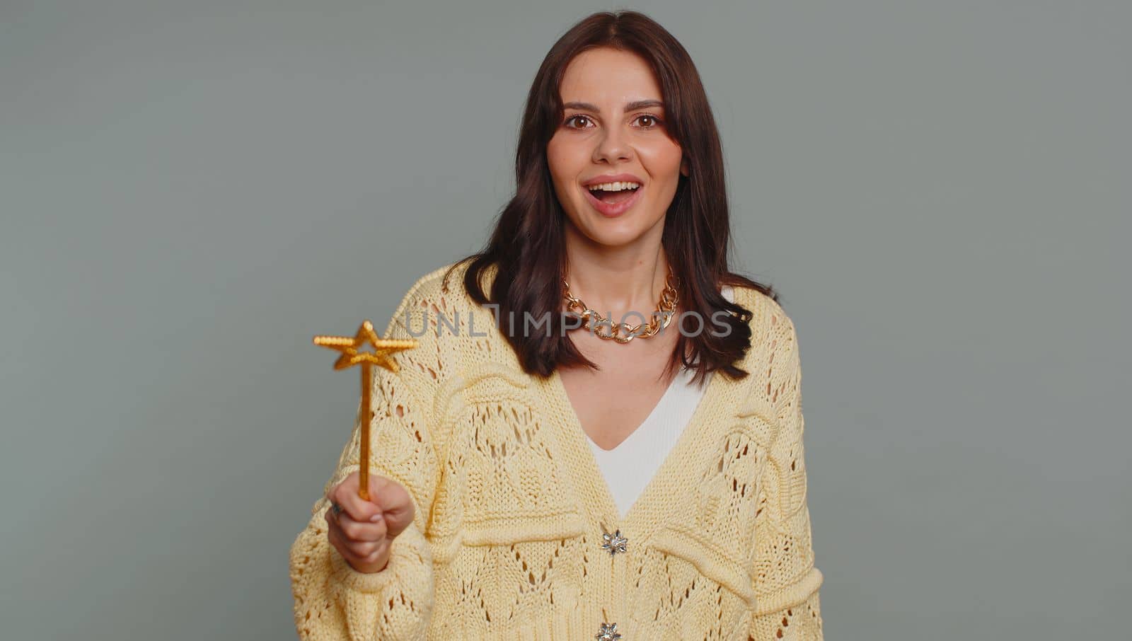 Magician witch woman gesturing with magic wand fairy stick, making wish come true, casting magician spell, advertising holidays sale discount. Young pretty girl isolated on gray studio background
