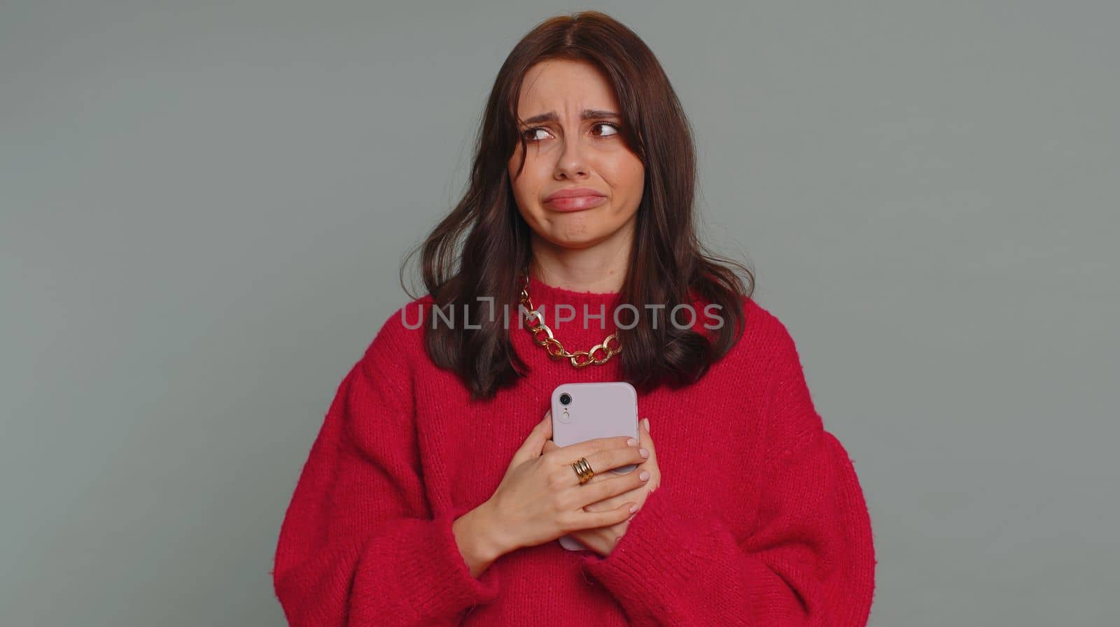 Hipster pretty woman use mobile cell phone typing browsing, loses becoming surprised sudden lottery results, bad fortune, loss, fail. Young girl isolated alone on gray studio wall background