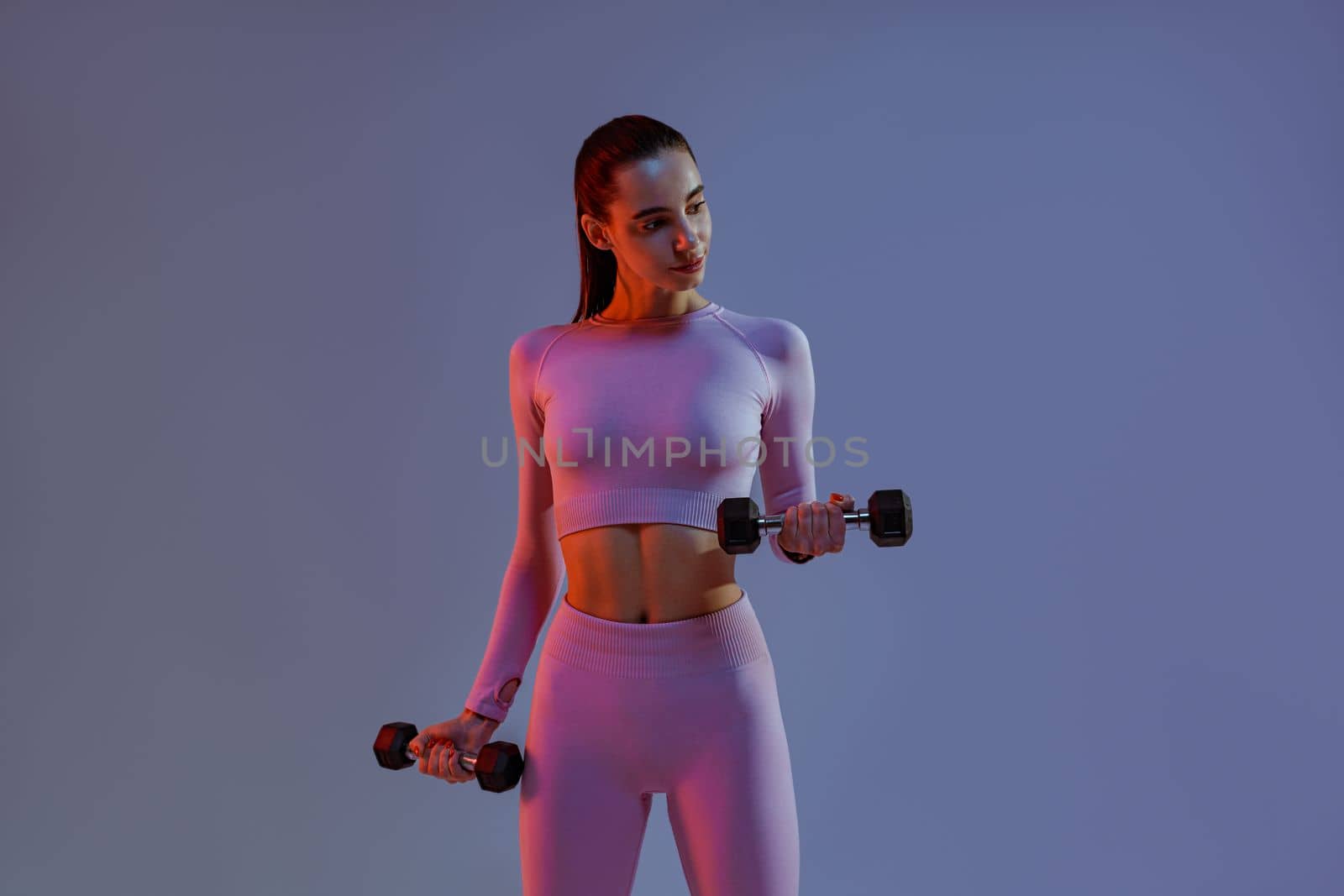 Woman doing exercises with dumbbells on studio background . Sport and healthy lifestyle