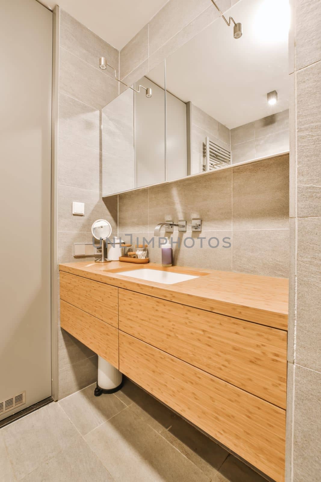a modern bathroom with wood cabinets and mirrors on the wall, along with a white toilet in the corner next to the sink