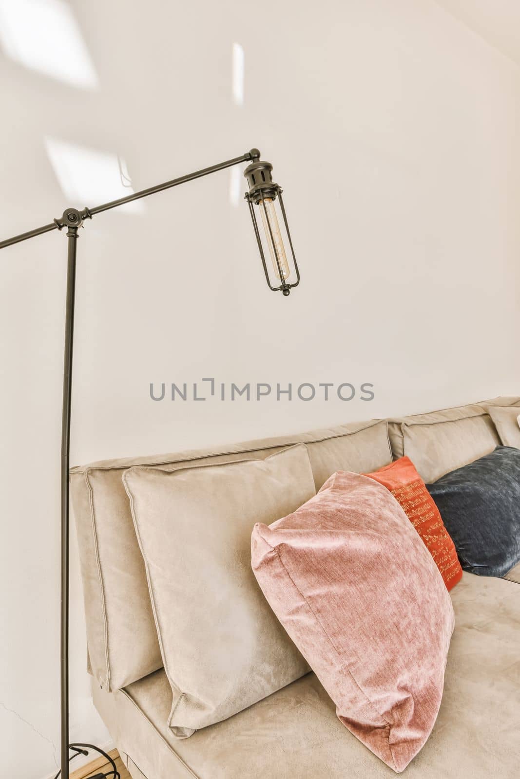 a living room with a couch, lamp and pillows on the sofa in front of the couch is white wall