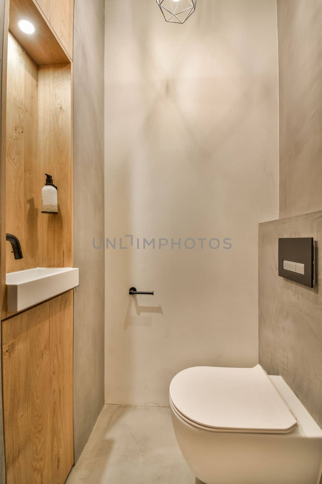 a bathroom with a toilet, sink and light fixture on the wall next to the toilet is a wooden cabinet