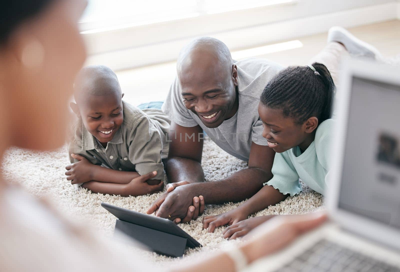 Family is the most important thing in the world. a family using s tablet while laying on the floor at home