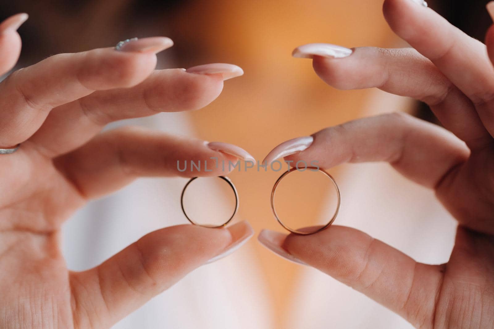 Close-up of two gold wedding rings in your hands by Lobachad