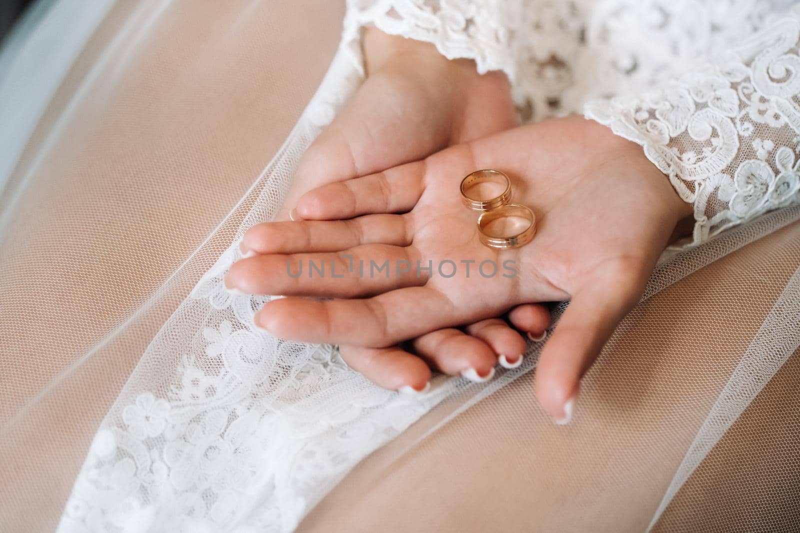 Close-up of two gold wedding rings in the palm of your hand by Lobachad