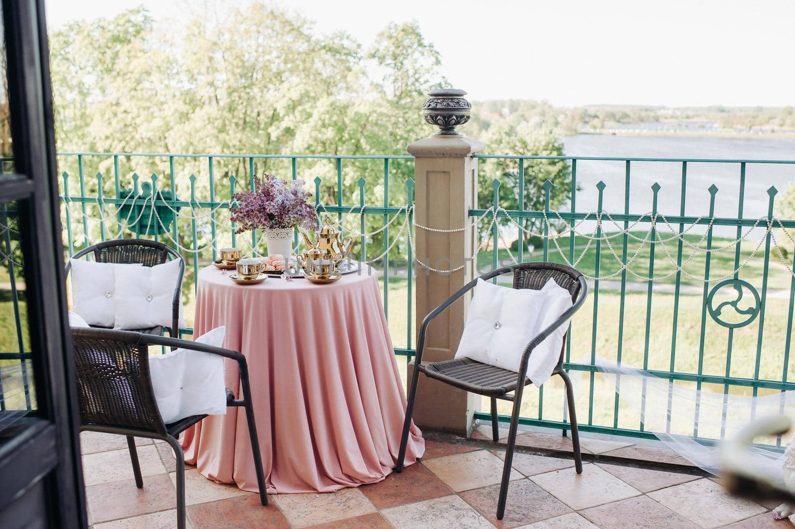 Delicate morning tea table setting with lilac flowers in Nesvizh castle, antique spoons and dishes on the table with a pink tablecloth.