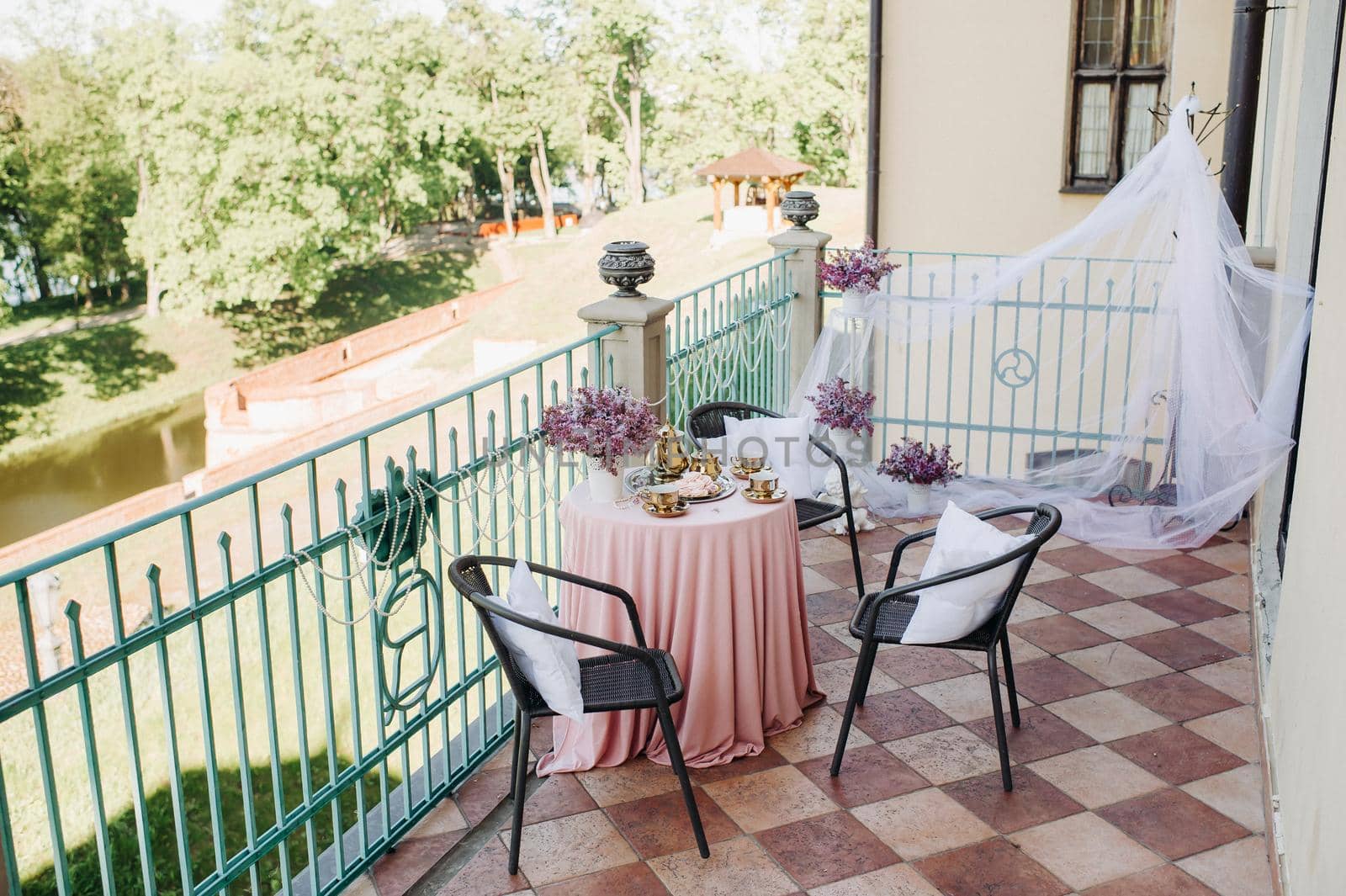 Delicate morning tea table setting with lilac flowers in Nesvizh castle, antique spoons and dishes on the table with a pink tablecloth.