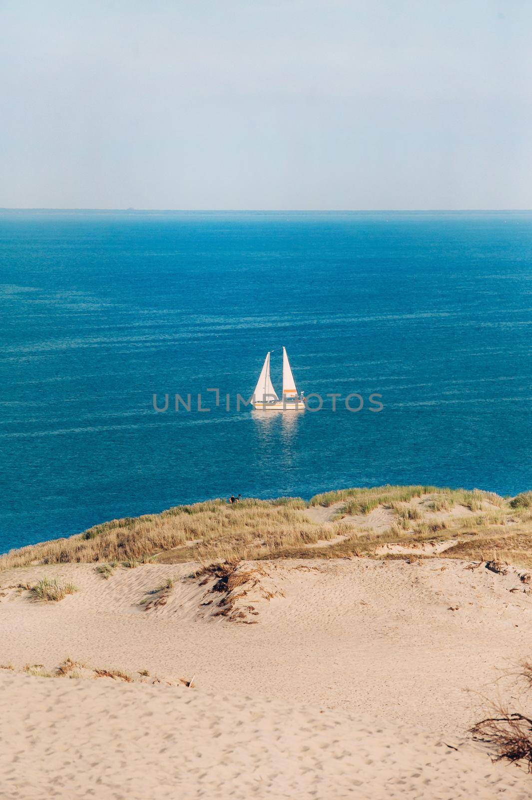 White Sailboat On the background of Dunes and Blue Sky in the sea.White sailboat in the Baltic sea.Lithuania.Nida.