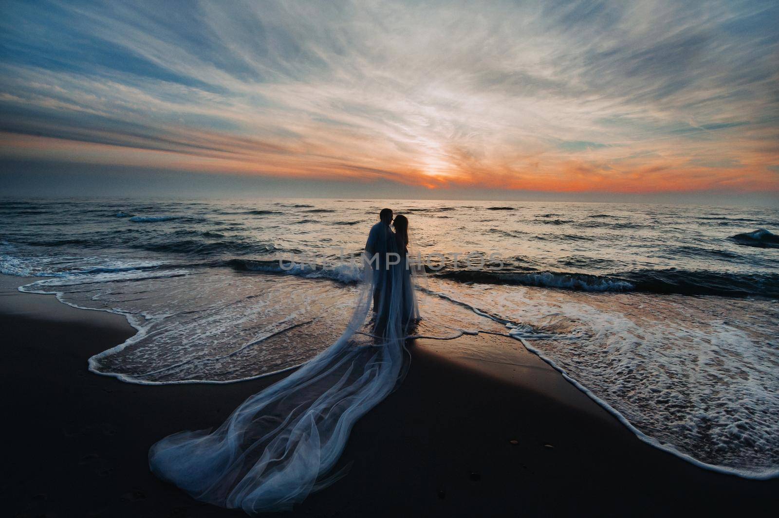 A couple in love at sunset on the background of the sea, an unrecognizable couple Portrait of a beautiful newlywed couple expecting a child. Photo, by Lobachad