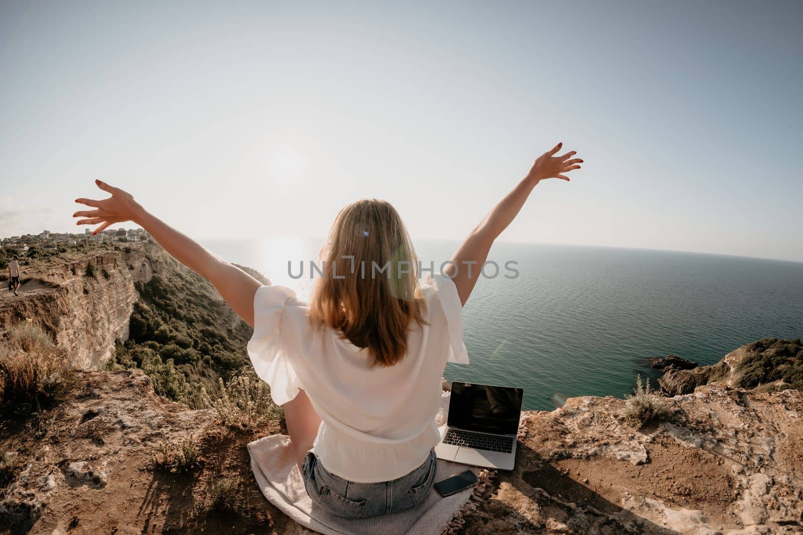 Woman sea laptop. Business woman in yellow hat working on laptop by sea. Close up on hands of pretty lady typing on computer outdoors summer day. Freelance, digital nomad, travel and holidays concept.