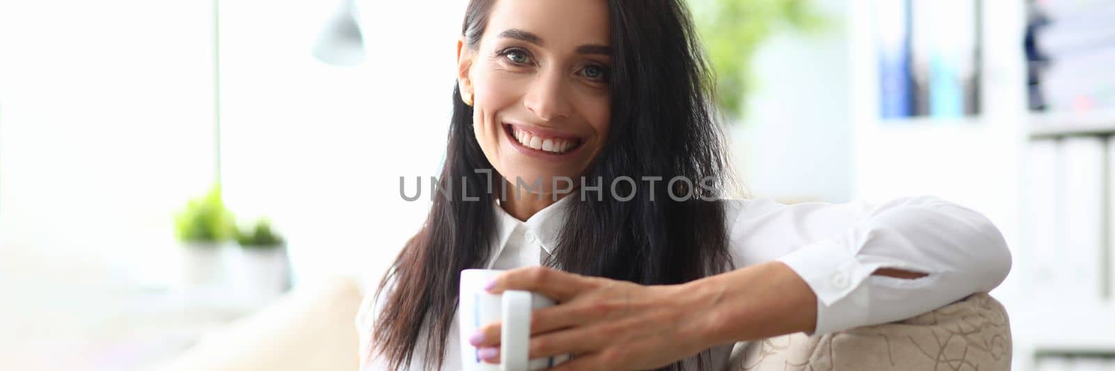 Portrait of smiling minded successful employee business woman in white shirt with cup. Concept of career achievement and rest in workplace