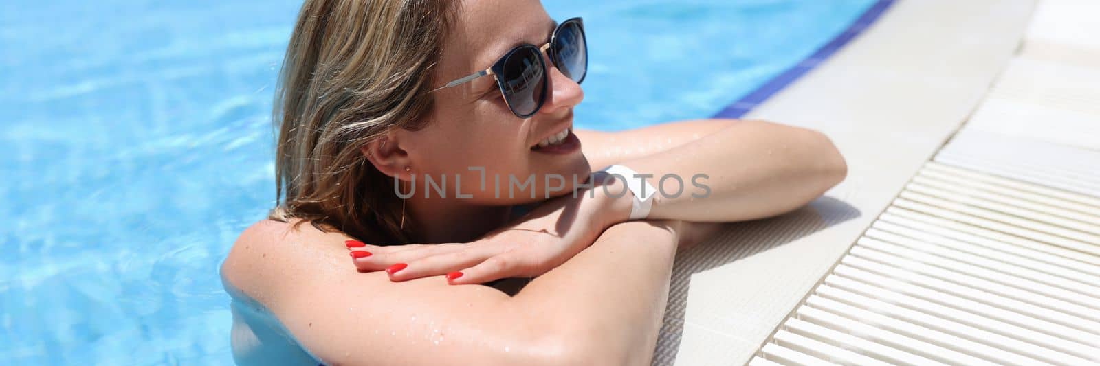 Portrait of beautiful woman in sunglasses in pool by kuprevich