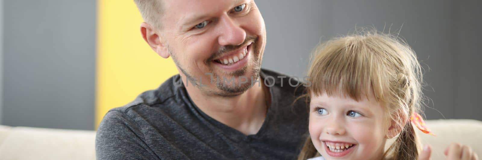 Happy dad holding cute cheerful daughter laughing and having good time together. Loving father and smiling little girl hugging and caring dad