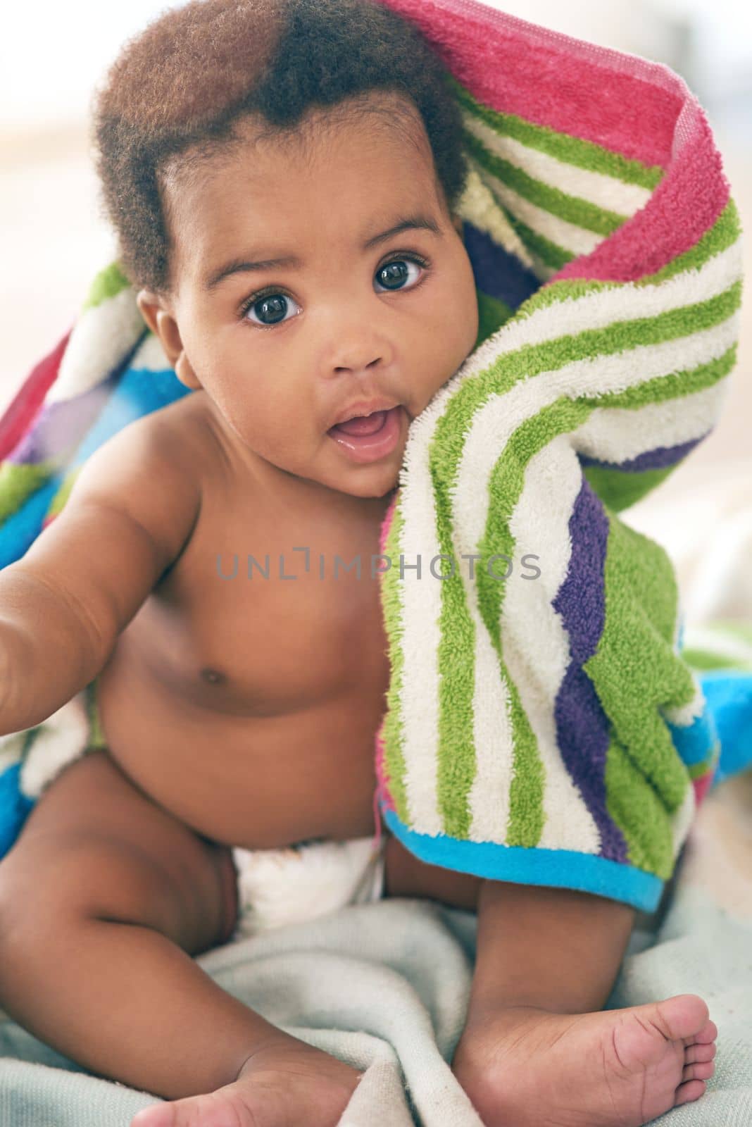 I love my blankie. an adorable baby girl covered in a colorful blanket at home. by YuriArcurs