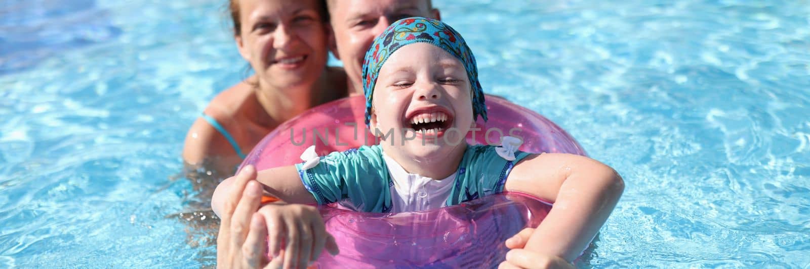 Happy laughing joyful family couple and baby in pool. Family vacation with children in water park