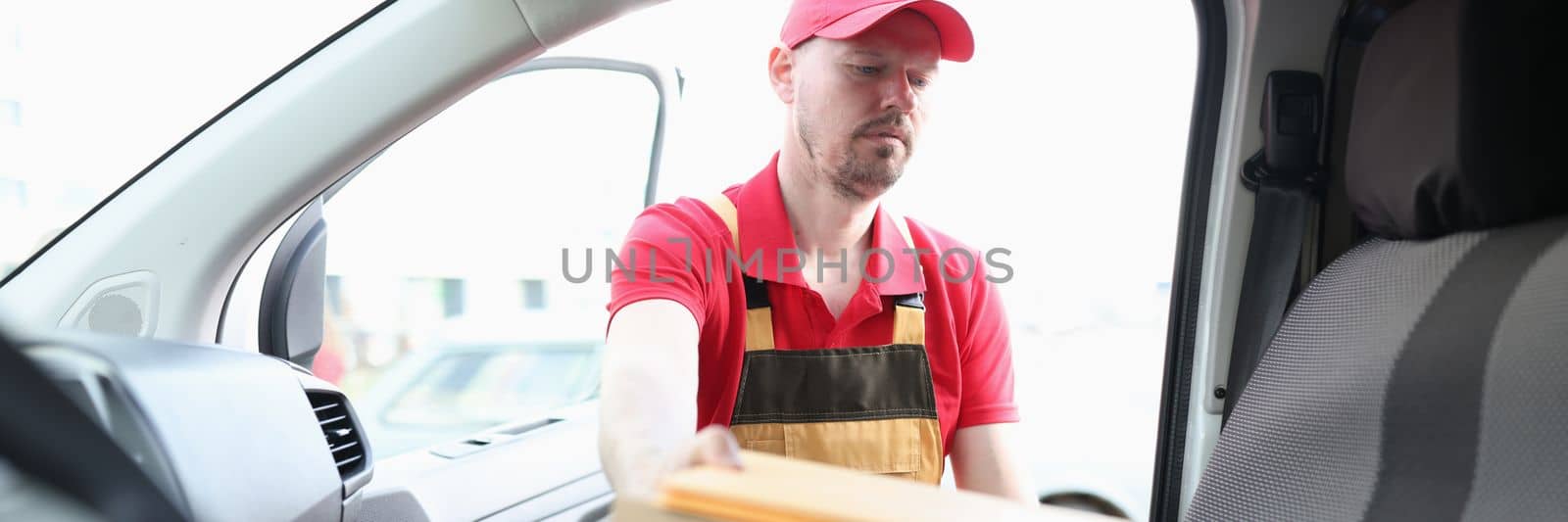 Young delivery man is loading boxes into car. Parcel delivery and logistics services