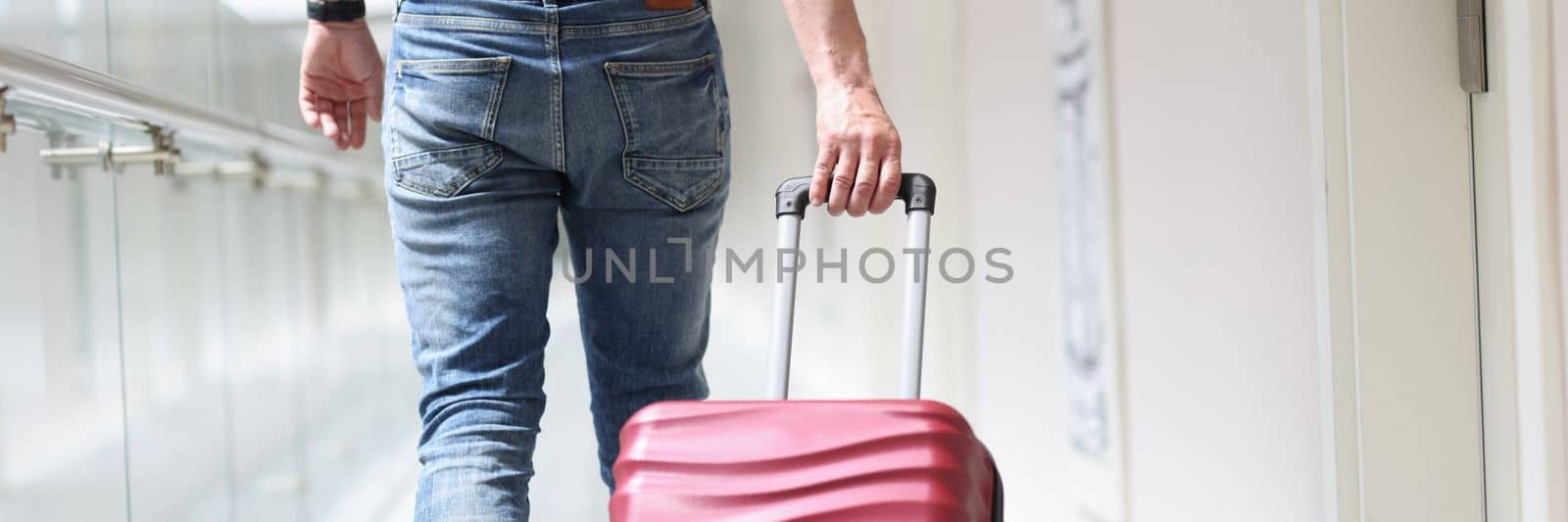 Male tourist pulls suitcase moving to luxury hotel. Booking and check-in at the hotel