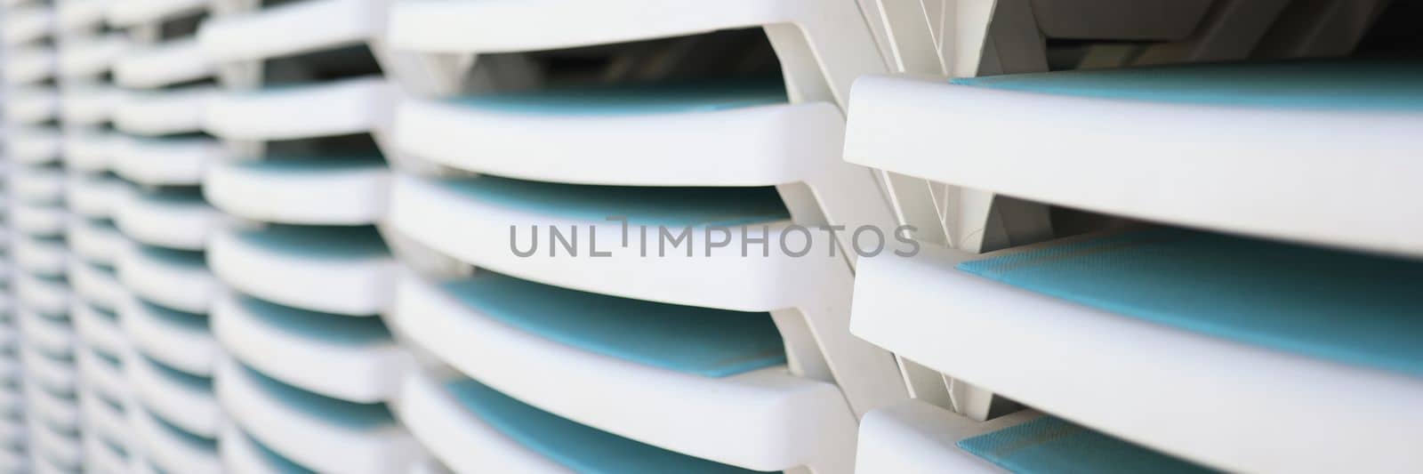 White plastic sun loungers stacked together on a sandy beach by kuprevich