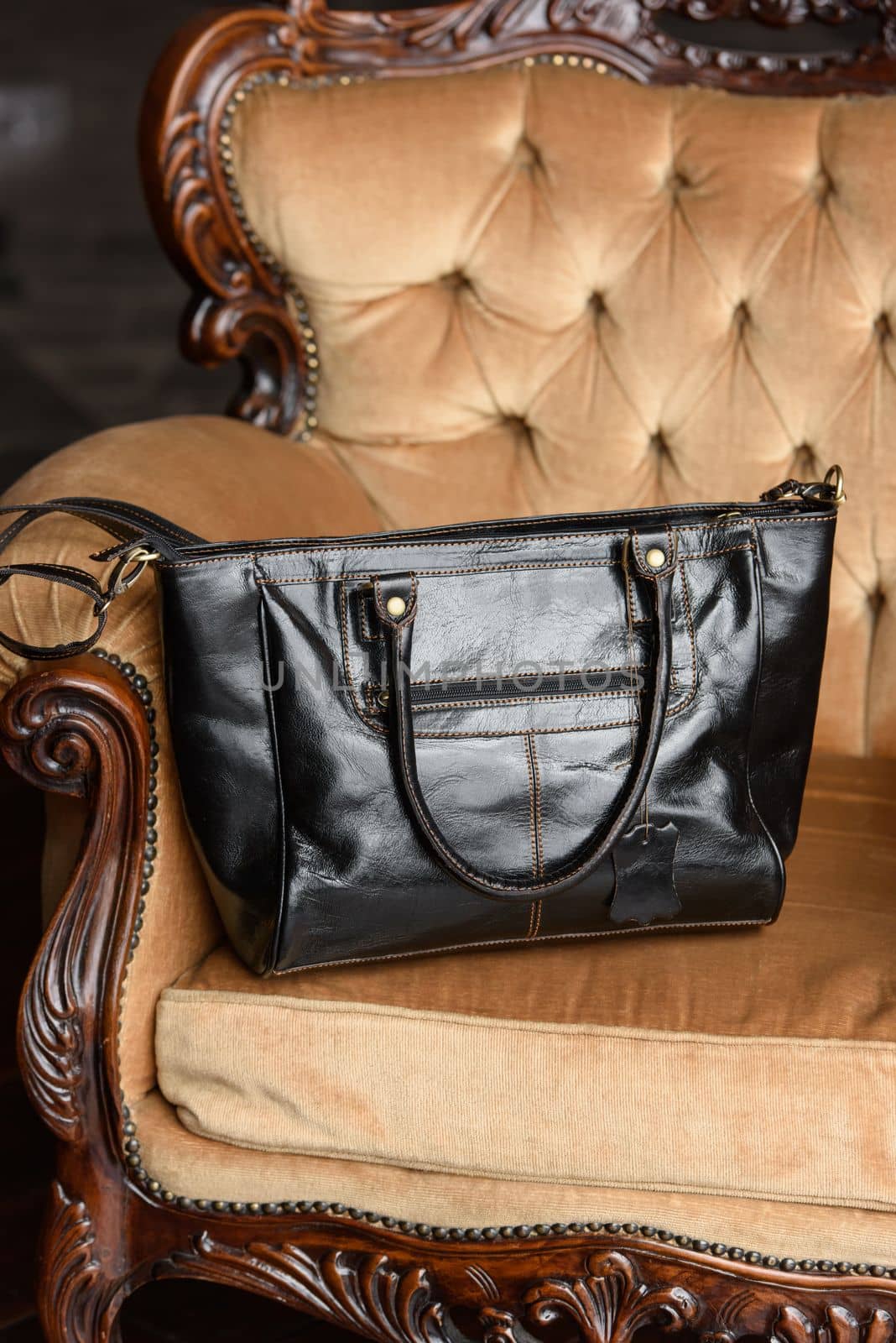 close-up photo of blackleather bag on a yellow velor vintage armchair. indoor photo