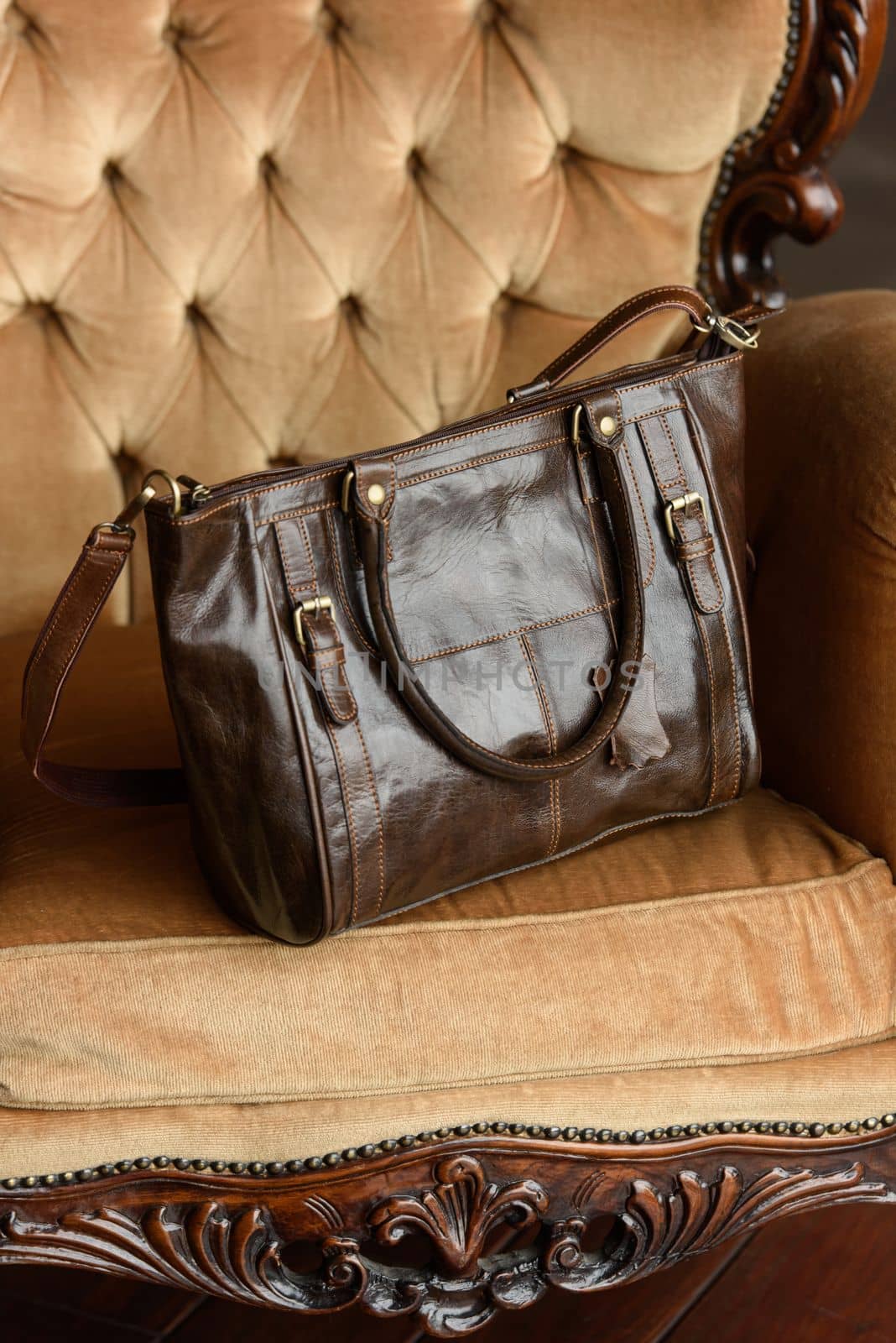 close-up photo of brown leather bag on a yellow velor vintage armchair. indoor photo