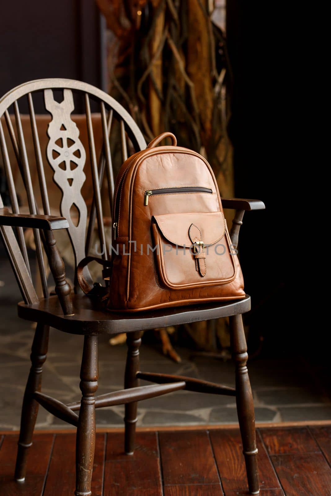 Brown leather backpack on the stylish chair. indoor photo