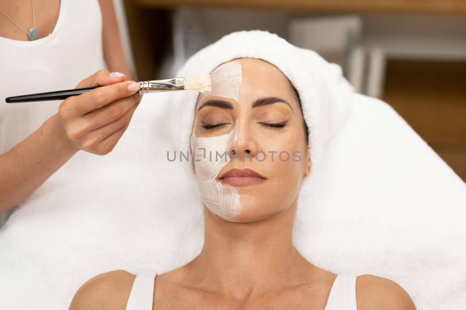 Aesthetics applying a mask to the face of a Middle-aged woman in modern wellness center. Beauty and Aesthetic concepts.
