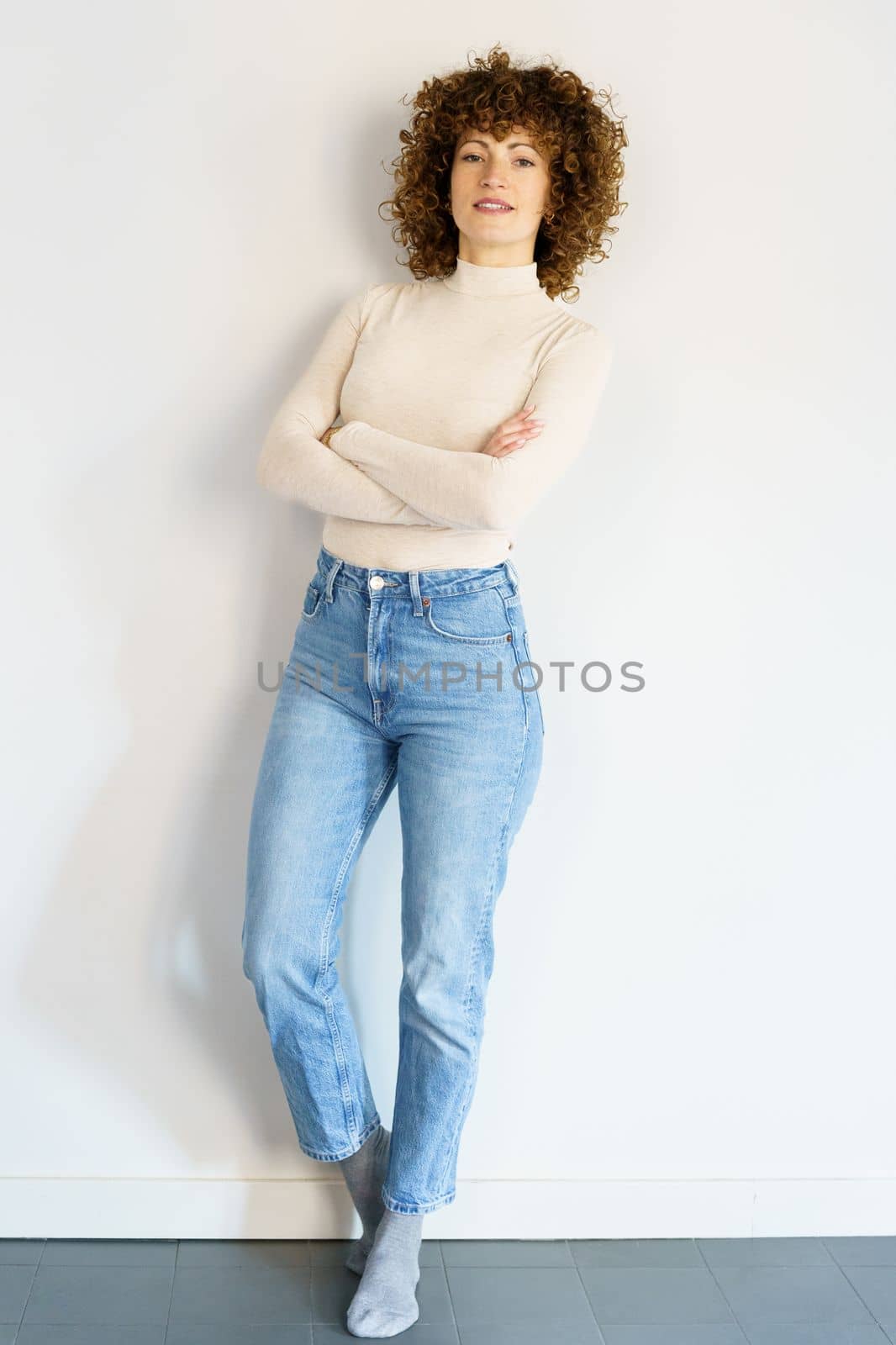 Confident woman standing against wall with crossed arms by javiindy