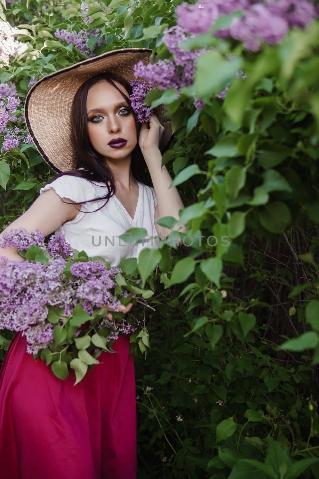 A fashionable girl with dark hair, a spring portrait in lilac tones in summer. Bright professional makeup