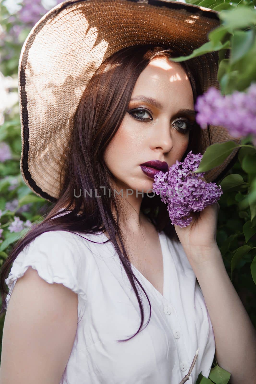 A fashionable girl with dark hair, a spring portrait in lilac tones in summer. Bright professional makeup