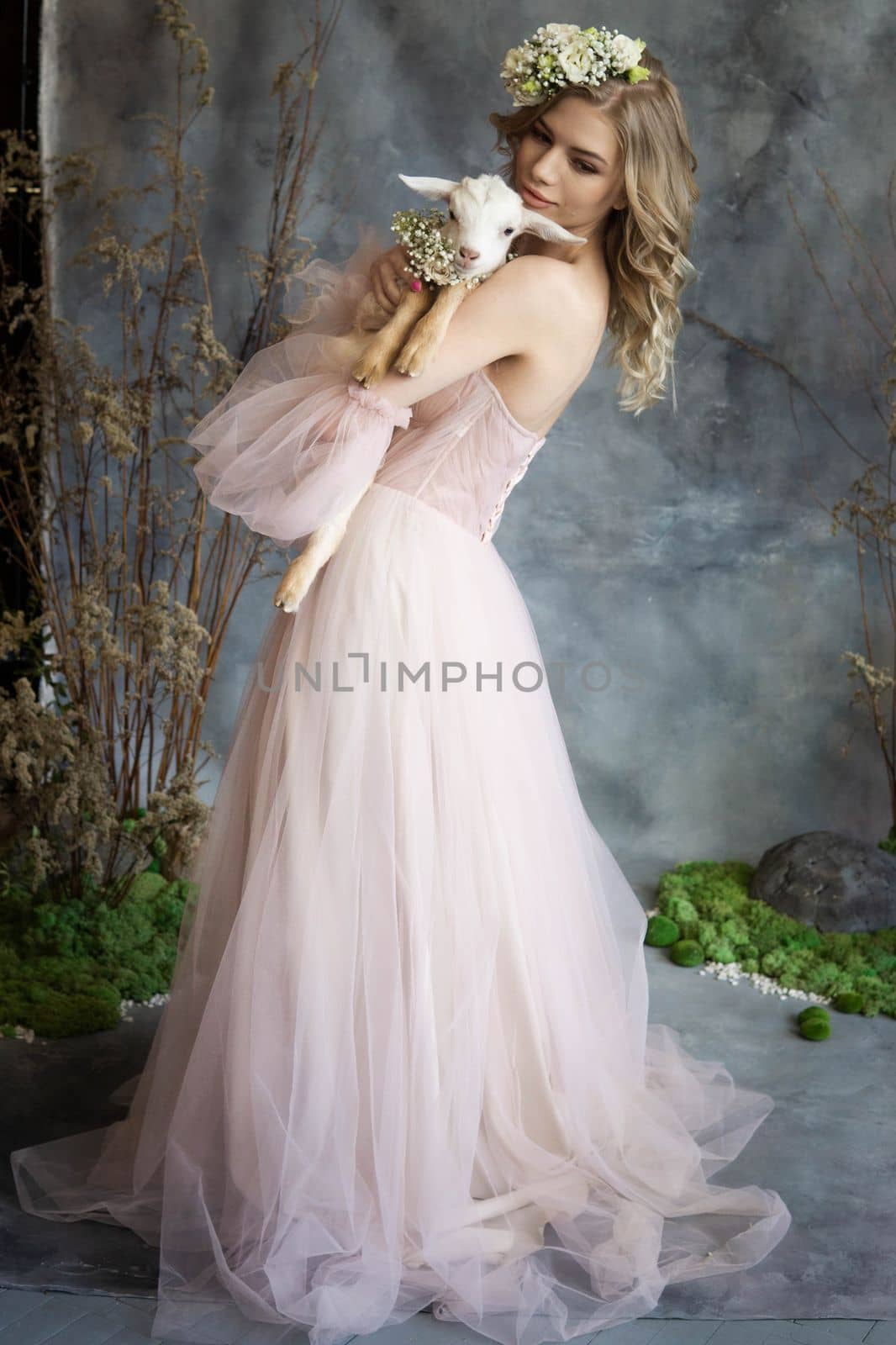 A young blonde woman in an airy pink dress with a white kid. Spring portrait of a woman